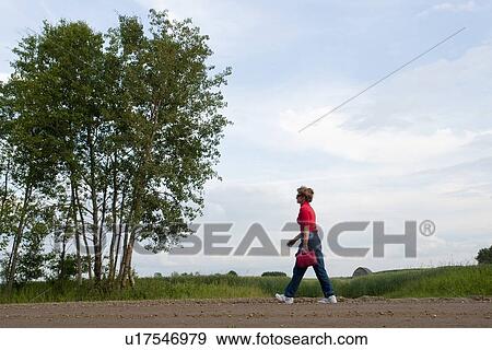 Woman holding gas can walks along gravelled country road, Manitoba, Canada View Large Photo Image Stock Photo - Woman holding gas can walks along gravelled country road, Manitoba, Canada. Fotosearch