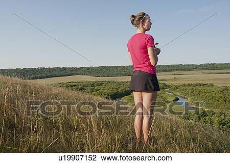 Stock Image - Woman holds flower on hillside, rural Manitoba, Canada. Fotosearch