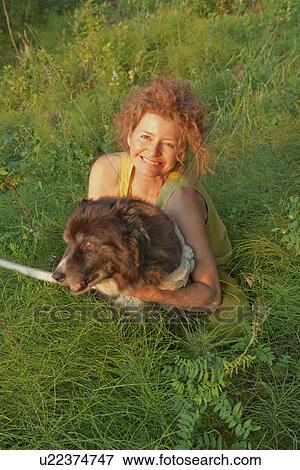 Stock Photo - Woman hugs her dog, seated outdoors, Clear Lake, Manitoba, Canada. Fotosearch