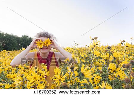Woman in a field of yellow flowers holds two flowers up to her eyes, Manitoba, Canada View Large Photo Image Stock Image - Woman in a field of yellow flowers holds two flowers up to her eyes, Manitoba, Canada. Fotosearch
