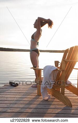 Stock Photo - Woman in bathing suit on dock at sunrise, Clear Lake, Manitoba, Canada. Fotosearch