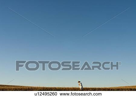 Stock Image - Woman in lab coat beside field, Manitoba, Canada. Fotosearch