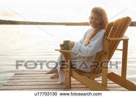 Woman in robe seated on deck chair on dock, Clear Lake, Manitoba, Canada View Large Photo Image Stock Image - Woman in robe seated on deck chair on dock, Clear Lake, Manitoba, Canada. Fotosearch