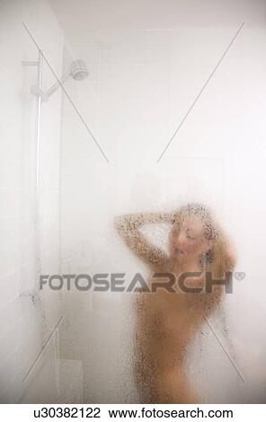 Woman in steamy shower stall with low flow faucet. Stock Image