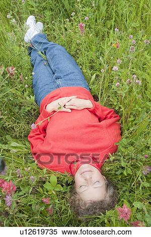 Woman laying back in a field of flowers, Manitoba, Canada View Large Photo Image Stock Photography - Woman laying back in a field of flowers, Manitoba, Canada. Fotosearch