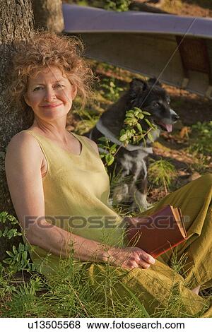 Woman leans against tree reading book, with dog, Clear Lake, Riding Mountain National Park, Manitoba, Canada View Large Photo Image Stock Photo - Woman leans against tree reading book, with dog, Clear Lake, Riding Mountain National Park, Manitoba, Canada. Fotosearch