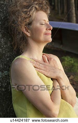 Woman leans against tree with hands folded over chest, Clear Lake, Manitoba View Large Photo Image Stock Photo - Woman leans against tree with hands folded over chest, Clear Lake, Manitoba. Fotosearch