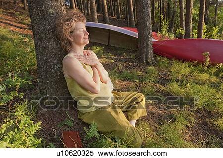 Woman leans against tree with hands folded over chest, Clear Lake, Manitoba View Large Photo Image Stock Photography - Woman leans against tree with hands folded over chest, Clear Lake, Manitoba. Fotosearch