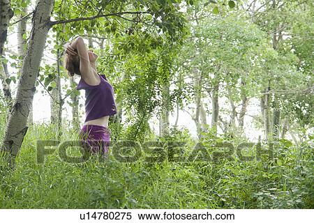 Stock Photography - Woman looking upward in grove of poplar trees, Manitoba, Canada. Fotosearch