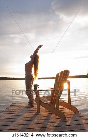 Woman reaching upward on dock at sunset, Clear Lake, Manitoba, Canada View Large Photo Image Picture - Woman reaching upward on dock at sunset, Clear Lake, Manitoba, Canada. Fotosearch