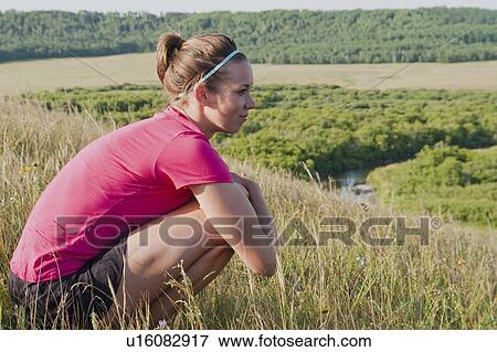 Woman rests on haunches on hillside, rural Manitoba, Canada View Large Photo Image Stock Photo - Woman rests on haunches on hillside, rural Manitoba, Canada. Fotosearch