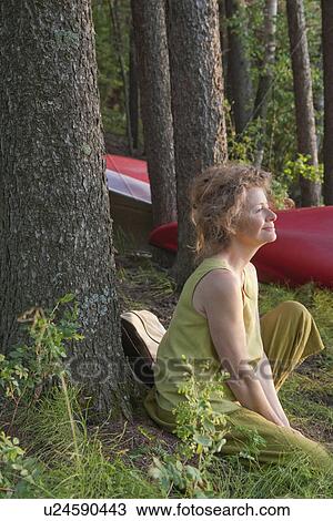 Stock Image - Woman seated beside tree, Clear Lake, Manitoba. Fotosearch