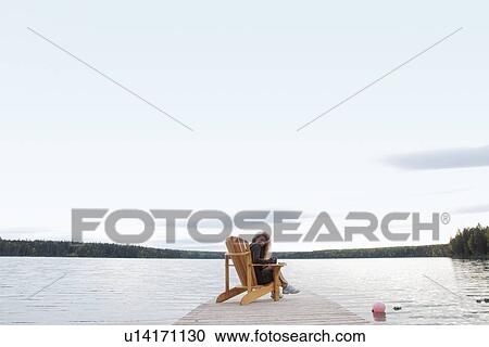 Woman seated on deck chair on dock, Clear Lake, Manitoba, Canada View Large Photo Image Stock Image - Woman seated on deck chair on dock, Clear Lake, Manitoba, Canada. Fotosearch