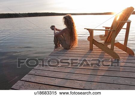 Woman seated on dock holding cup of coffee, Clear Lake, Manitoba View Large Photo Image Stock Photography - Woman seated on dock holding cup of coffee, Clear Lake, Manitoba. Fotosearch