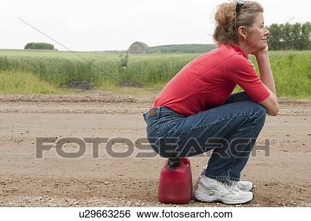 Woman seated on jerry can, gravelled rural road, Manitoba, Canada View Large Photo Image Stock Photograph - Woman seated on jerry can, gravelled rural road, Manitoba, Canada. Fotosearch