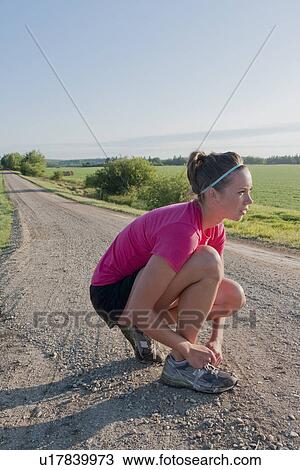 Stock Image - Woman ties shoe, rural Manitoba, Canada. Fotosearch