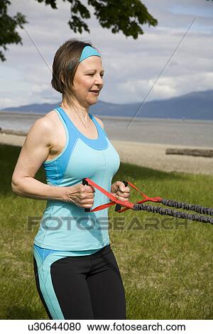 Stock Image - Woman using yoga bands, Vancouver, BC. Fotosearch