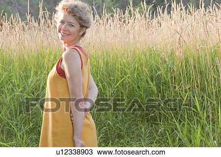 Stock Image - Woman with basket beside tall grass, Manitoba, Canada. Fotosearch