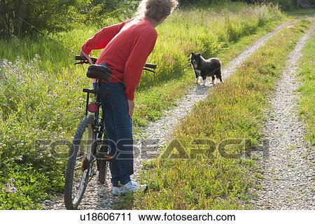 Woman with bicycle on country road with dog, Manitoba, Canada View Large Photo Image Stock Image - Woman with bicycle on country road with dog, Manitoba, Canada. Fotosearch