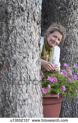 Stock Photo - Women between two trees beside flower pot, Manitoba, Canada. Fotosearch