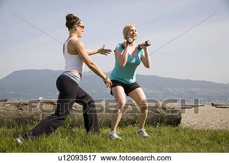 Stock Photo - Yoga Instructor and woman using weights in park, Vancouver. BC. Fotosearch