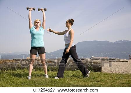 Stock Photo - Yoga Instructor and woman using weights in park, Vancouver. BC. Fotosearch