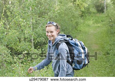 Stock Photo - Young girl hiking stops to pick saskatoon berry, Manitoba, Canada. Fotosearch