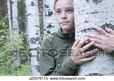 Stock Photography - Young girl with arm around tree, Manitoba, Canada. Fotosearch