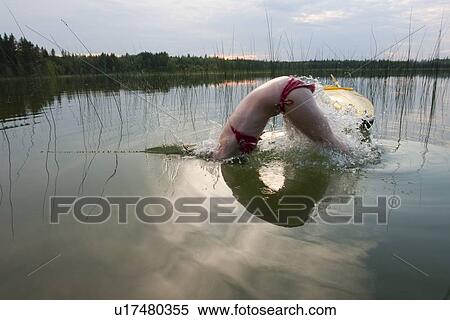 Stock Photography - Young woman diving into water, beside kayak, Lake Katherine, Riding Mountain National Park, Manitoba, Canada. Fotosearch