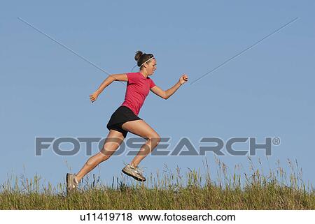 Stock Photo - Young woman running in profile, Manitoba, Canada. Fotosearch