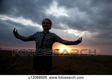Stock Photograph - Silhouette of girl against Kenya sky at sunset. Fotosearch