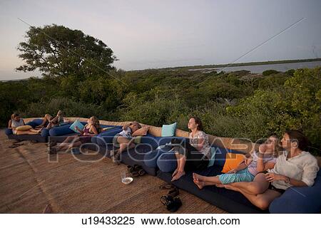 Stock Photography - Tourists on lounge chairs at Manda Bay Resort in Kenya Africa. Fotosearch