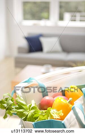 Stock Image - Bag of vegetables on chair in living room. Fotosearch