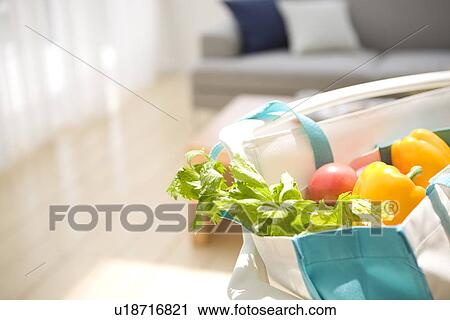 Stock Image - Bag of vegetables on chair in living room. Fotosearch