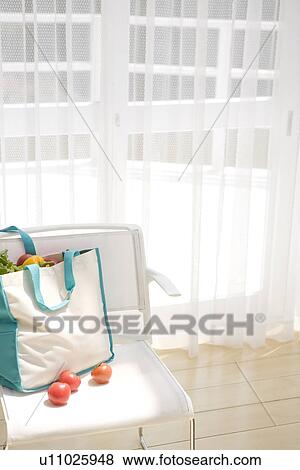 Stock Photo - Bag of vegetables on chair near window. Fotosearch