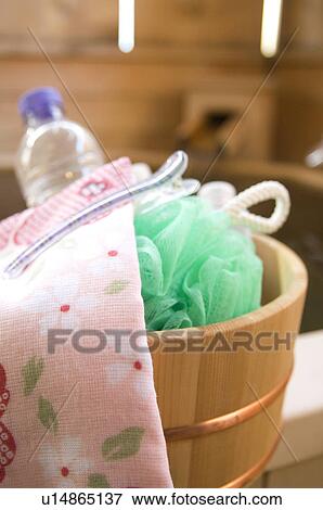 Stock Photo - Bamboo bucket containing towel, loofah and water bottle next to spa. Fotosearch
