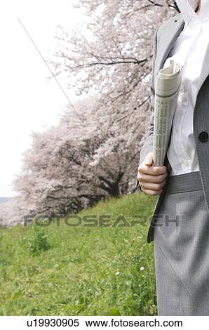 Stock Photography - Businesswoman holding a newspaper in a field. Fotosearch