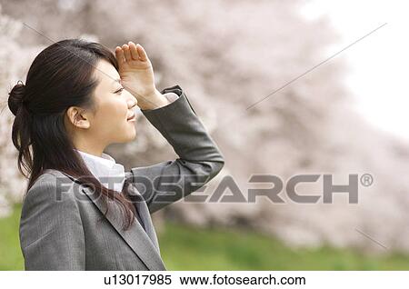 Stock Photography - Businesswoman in a field shielding her eyes. Fotosearch