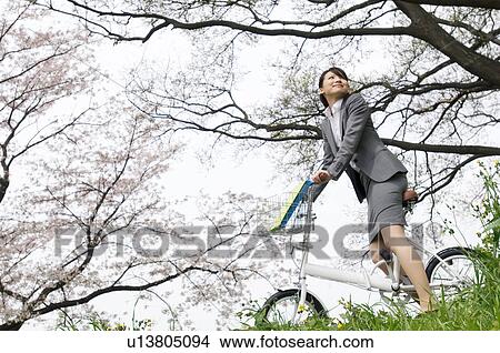 Businesswoman riding a bicycle in a field View Large Photo Image Picture - Businesswoman riding a bicycle in a field. Fotosearch