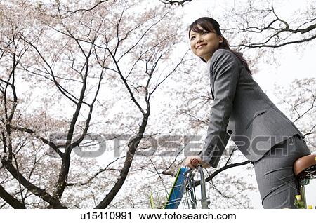 Businesswoman riding a bicycle in a field View Large Photo Image Stock Image - Businesswoman riding a bicycle in a field. Fotosearch