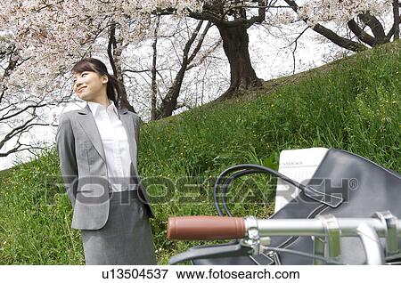 Stock Photo - Businesswoman standing underneath cherry trees. Fotosearch