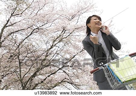 Stock Image - Businesswoman talking on cellphone in a field. Fotosearch