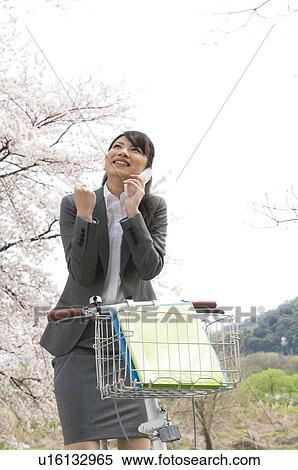 Stock Photography - Businesswoman talking on cellphone in a field. Fotosearch