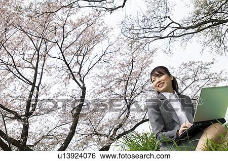 Stock Photograph - Businesswoman using laptop in a field. Fotosearch