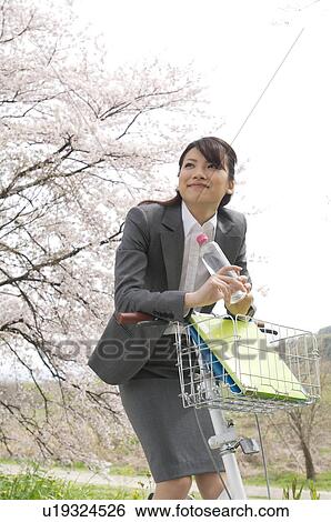 Businesswoman with a bicycle in a field View Large Photo Image Stock Photograph - Businesswoman with a bicycle in a field. Fotosearch