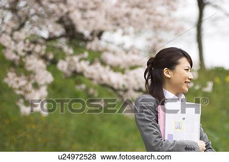Stock Photo - Businesswoman with some paperwork in a field. Fotosearch