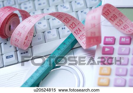 Stock Photography - Calculator and tape measure on laptop. Fotosearch
