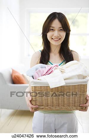 Cheerful young woman holding laundry View Large Photo Image Stock Photograph - Cheerful young woman holding laundry. Fotosearch