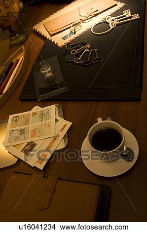 Picture - Coffee cup on desk with keys, postage stamps and air mail. Fotosearch
