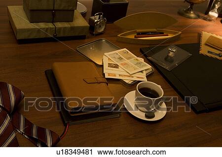 Stock Image - Coffee cup, tie and diary on desk. Fotosearch